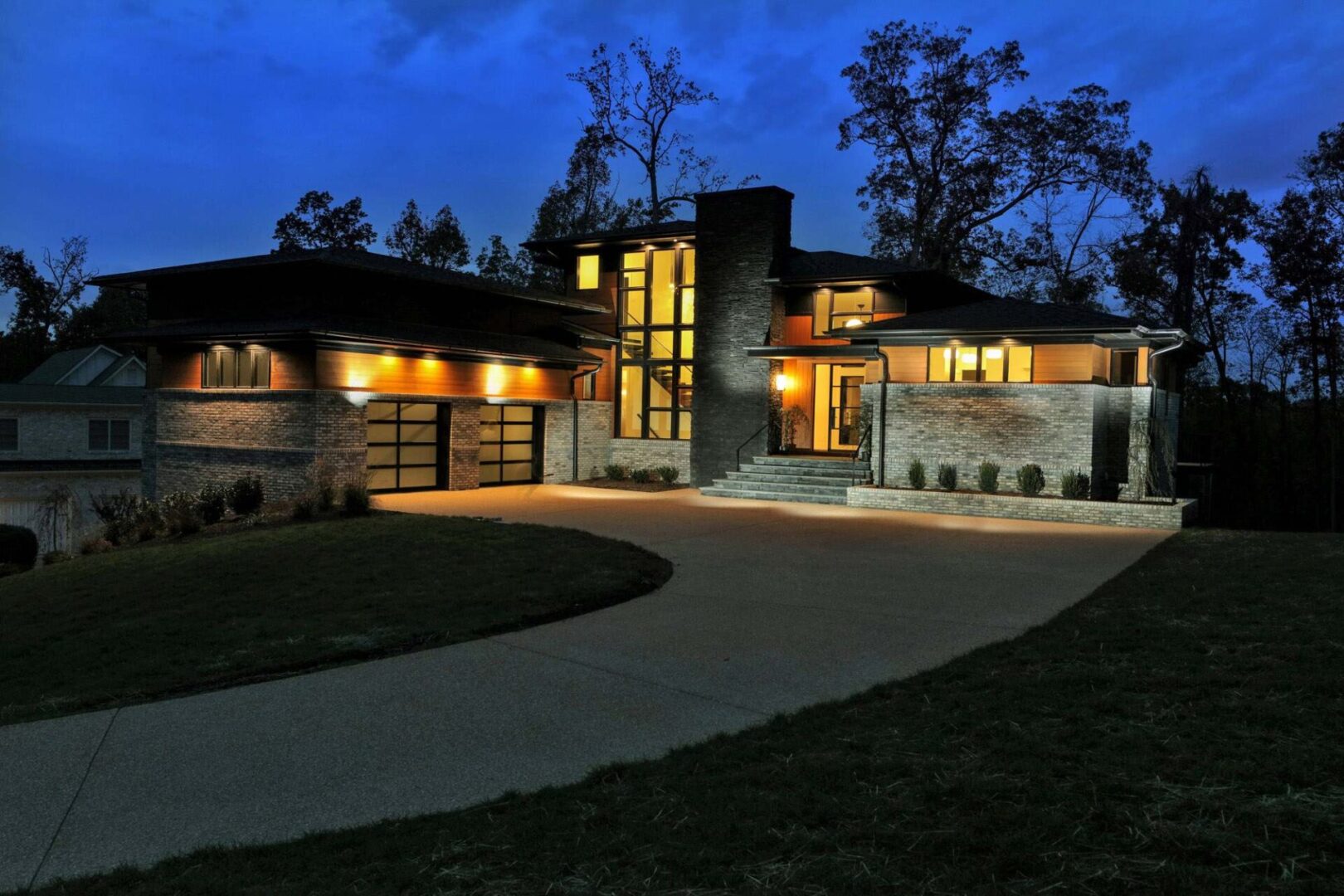A large modern style home with a driveway at night.