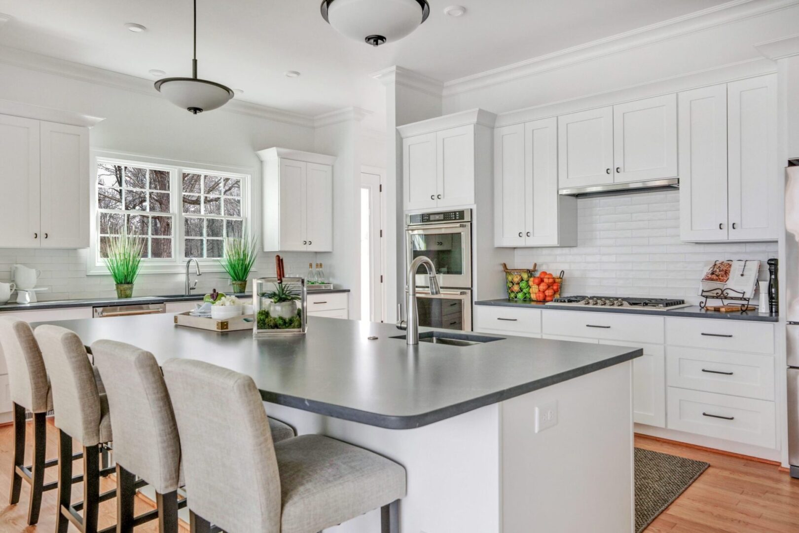 A kitchen with white cabinets and gray countertops.