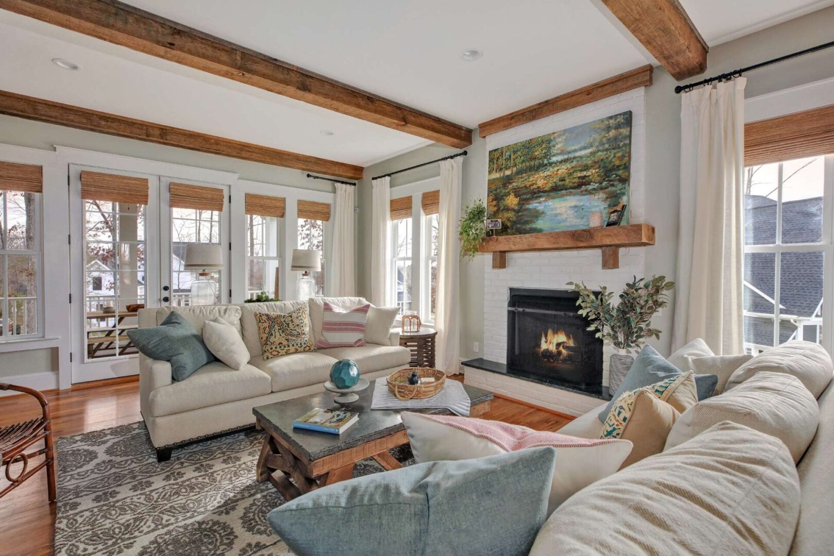 A living room with white furniture and wood beams.