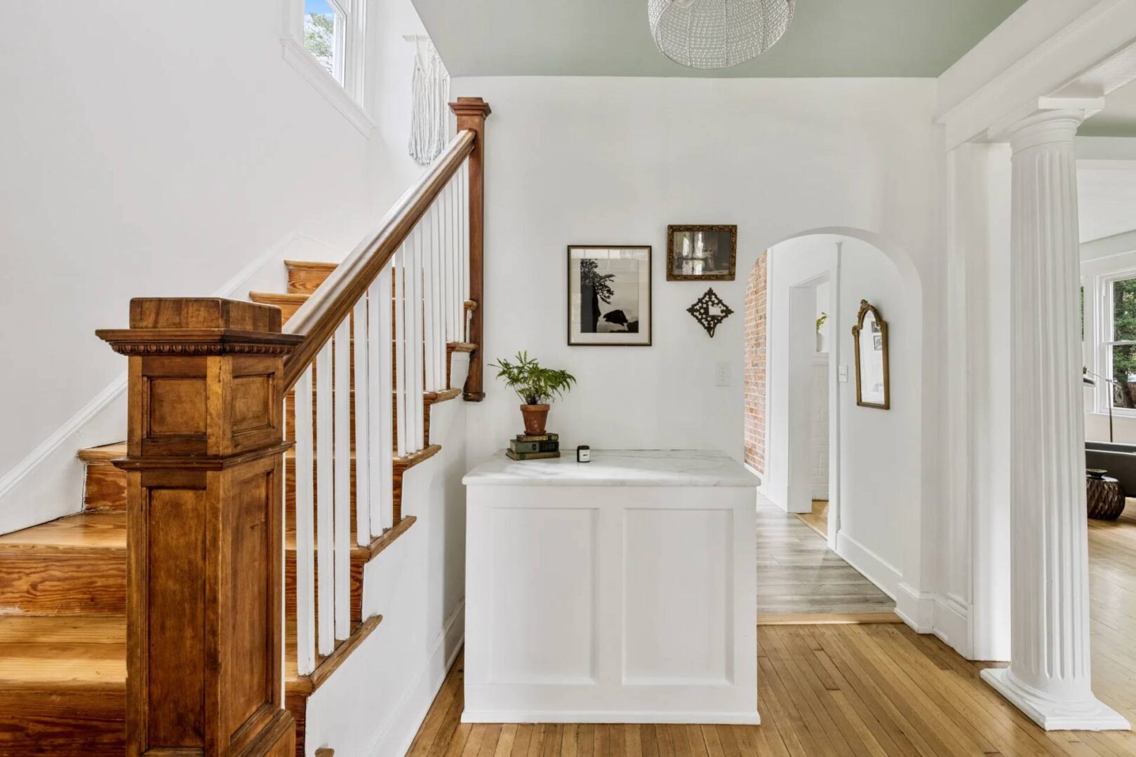 A white foyer with wood floors and a staircase.